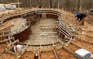 Inground pool under construction with steel rebar and wooden framing in a wooded area