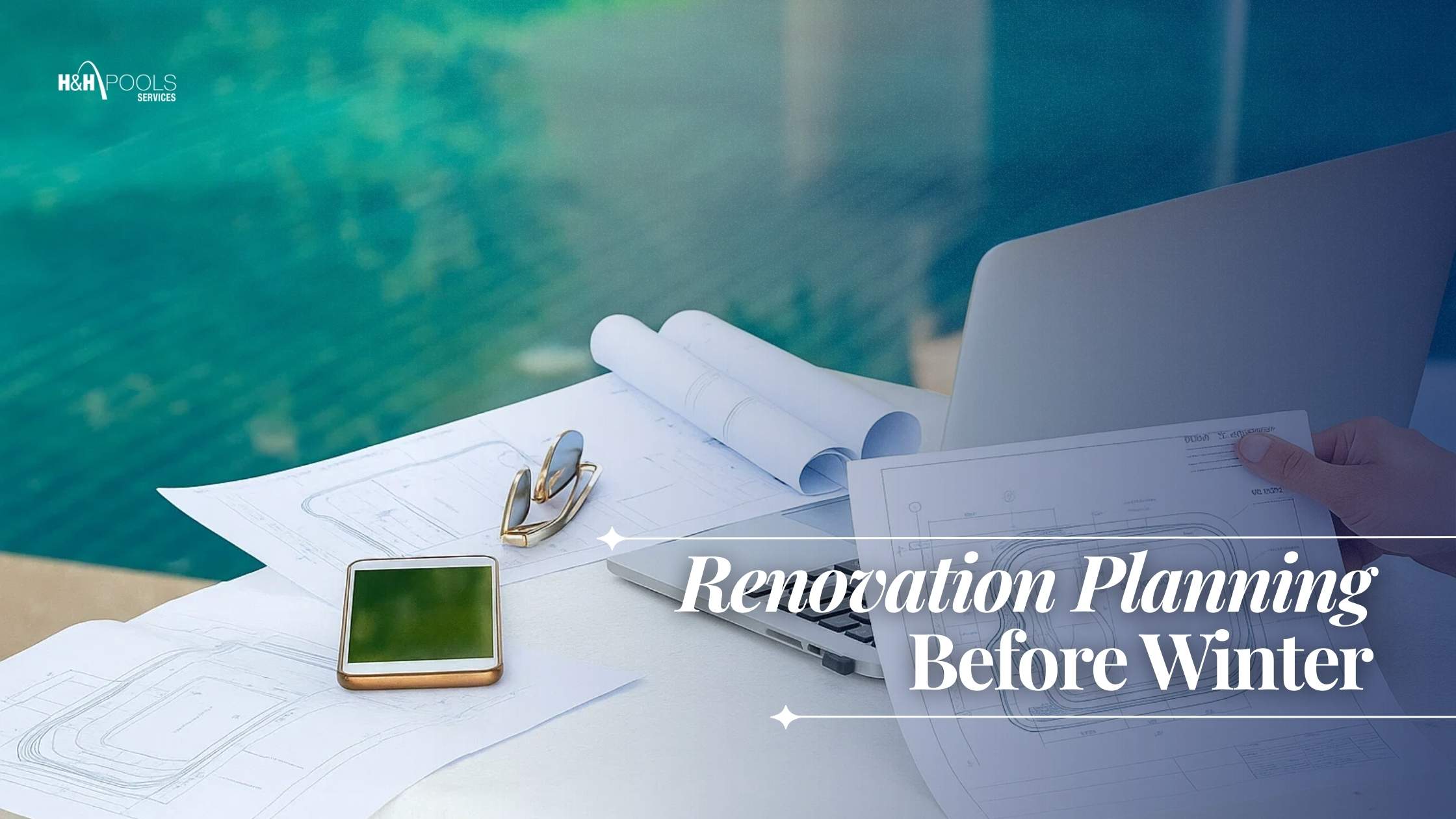 H&H_October 2025_blog1_How to winterize a pool renovation planning before winter Close-up of poolside renovation planning with blueprints, smartphone, eyeglasses, and laptop on a table, with a pool in the background.